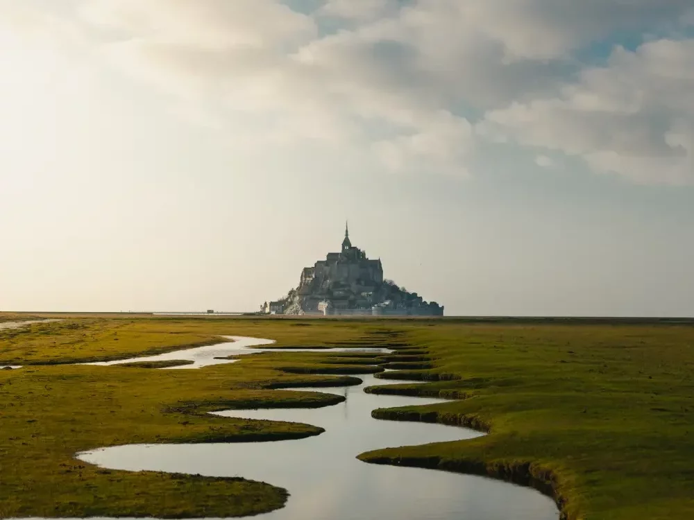 stunning view of the mont saint michel in france, far in the background with the bay at low tide on the foreground